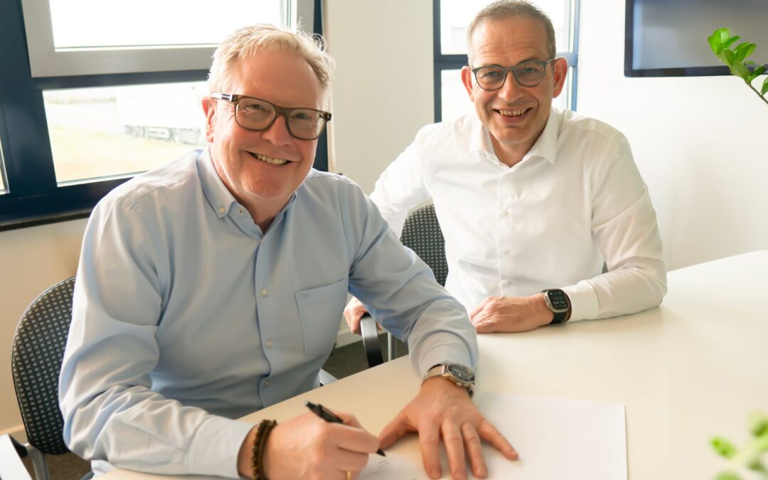 Zwei lächelnde Männer bei der Vertragsunterschrift